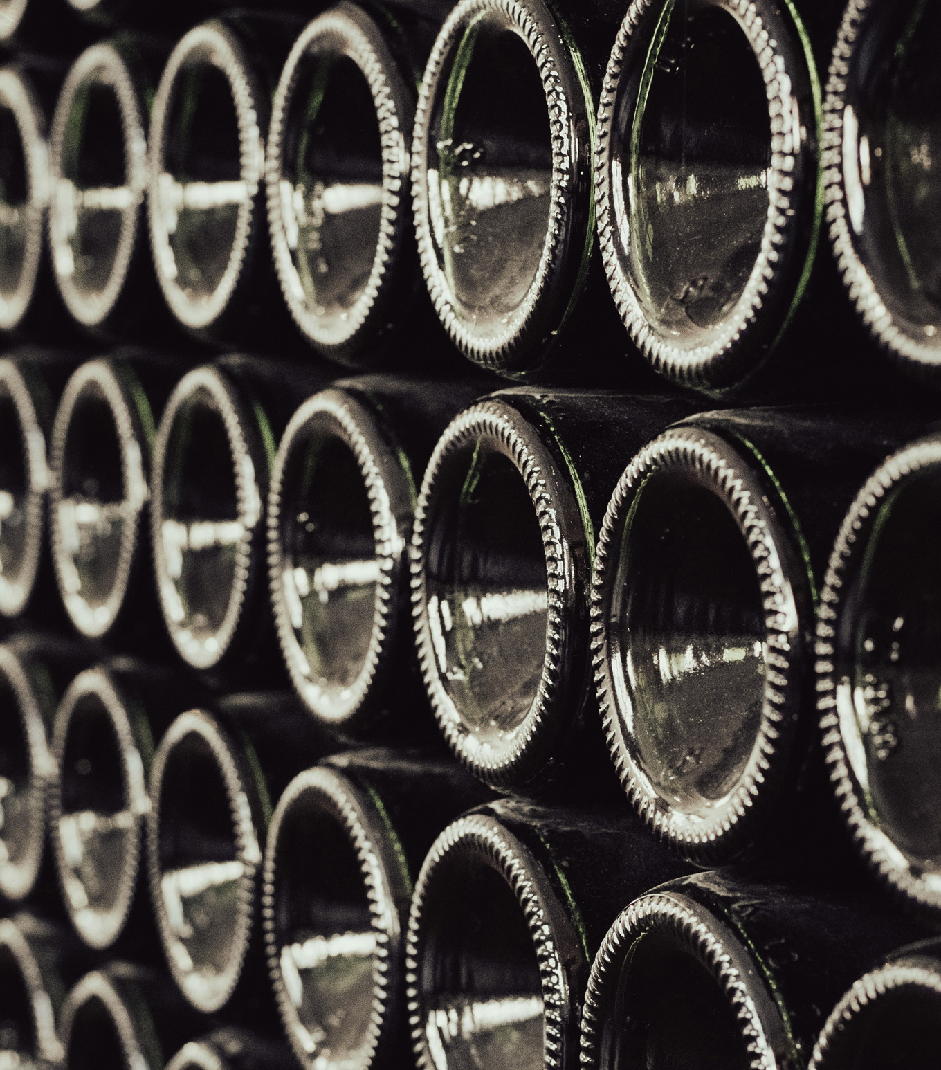 Close up of the bottom ends of Prosecco bottles that are stacked horizontally in a grid pattern